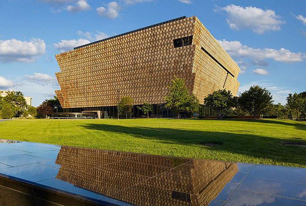 A building with a large square structure, a golden color structure. A front-facing view of the National Museum of African American History in Washington D.C.